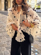 Une blouse semi-transparent en mousseline, couleur crème imprimée de grands pois noirs.